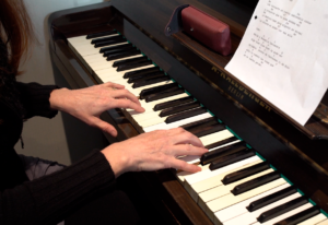 Las manos de una mujer tocando una melodía en el piano en una clase del Estudio Samela de Educación Musical (ESSEM)
